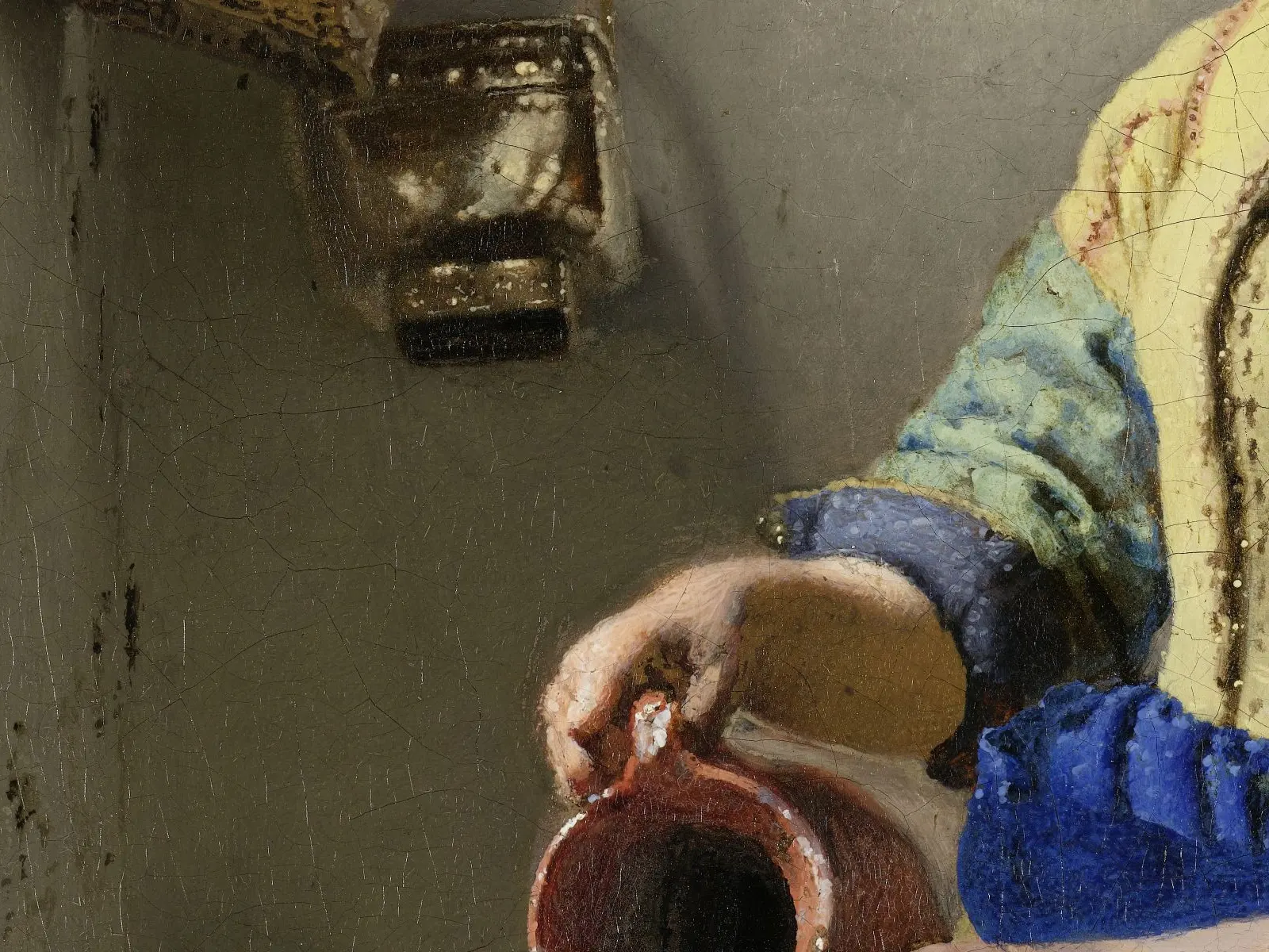 The maid's right hand grips the handle of a reddish jug, with bare, finely cracked wall paint above it and a metal pot hanging higher up.