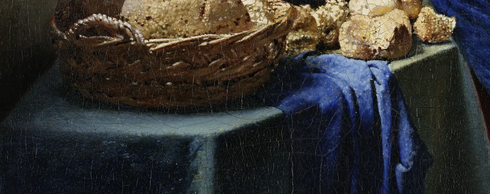 The tabletop: its left end slants up to the right against a dark background, its front band is lit, and its right-hand edge rises at two different slants on either side of a blue cloth.